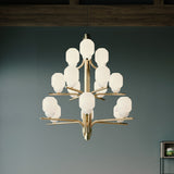 Faronne 15 Light Glass Chandelier in polished brass, with opal glass barrel shades across three tiers on a branching iron frame, shown hanging in a room with teal walls.