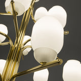 Close-up of the Faronne 15 Light Glass Chandelier, showing opal glass barrel shades with ribbed bases on curved polished brass arms against a dark background.