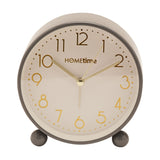 Round metal case alarm clock in glossy grey with a cream dial, gold Arabic numerals and hands, set on two round feet, shown on a plain white background.