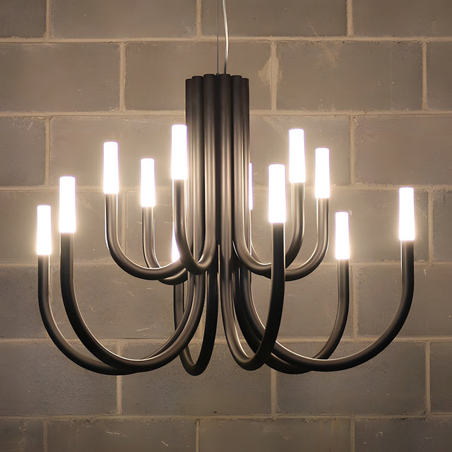 ThePalm LED 12 Light Chandelier in black iron with curved tiered arms and upright white acrylic heads, each glowing warm white, mounted against a tiled wall.