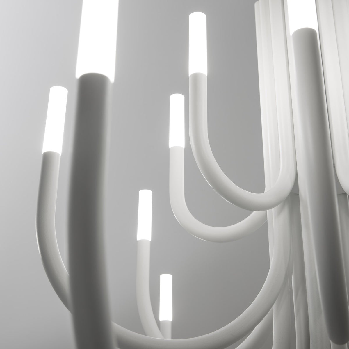 Close-up of ThePalm LED 18 Light Chandelier in white, showing curved acrylic and iron arms with glowing integrated LED tips against a light grey background.