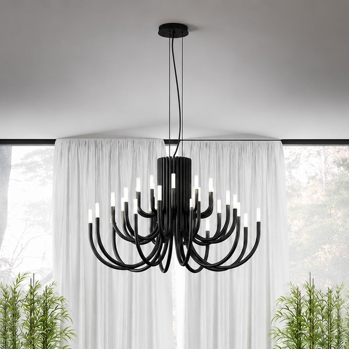 ThePalm LED 18 Light Chandelier in black, with curved arms in two tiers rising from a fluted column, hung above sheer curtains in a living room setting.