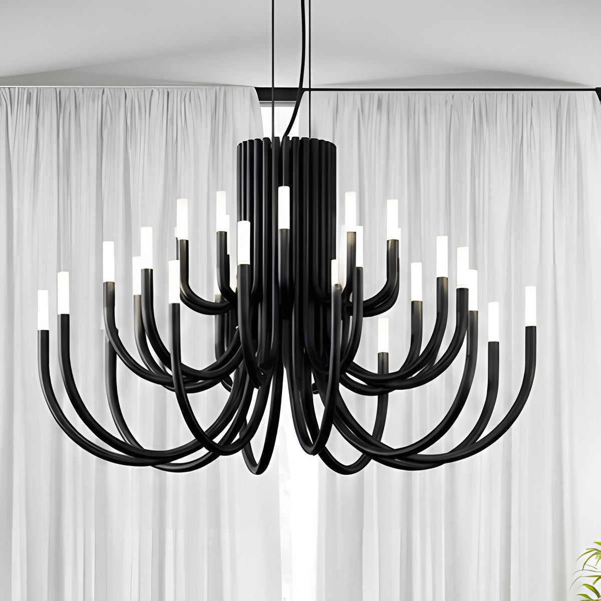 ThePalm LED 30 Light Chandelier in black, with curved iron arms rising in tiers from a fluted column, each tipped with glowing white acrylic, shown against sheer curtains.