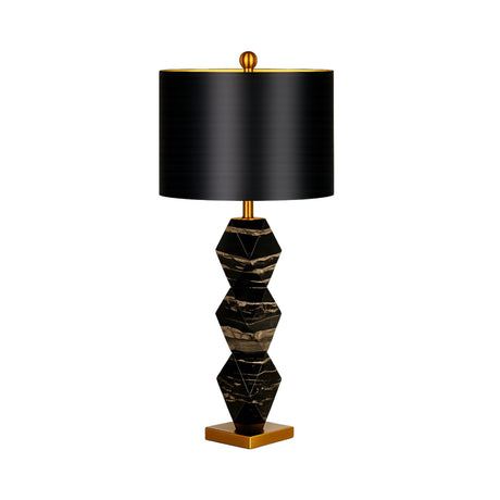 The Zerava 1 Light Faceted Marble Table Lamp features a geometric black and gold marble base, a large cylindrical black shade, and sculptural brass accents for a modern touch.