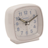 Square white plastic alarm clock with cushioned rounded corners, white dial, blue Arabic numerals, and black luminous hour and minute hands, shown on a plain background.