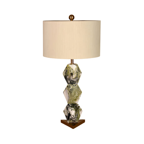 The Zerava 1 Light Faceted Marble Table Lamp in black and green has a geometric base of three stacked marbled hexagons and a gold triangular stand, topped with a beige cylindrical shade for striking sculptural style.