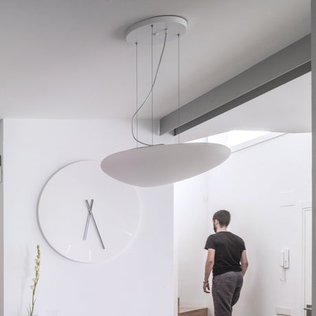 Stone LED Pendant Light in white, a flat pebble-shaped shade suspended on fine wires from a round ceiling canopy, shown above a hallway wall clock.