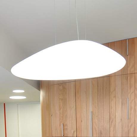 Stone LED Pendant Light in white, a flat pebble-shaped shade suspended on fine wires from a round ceiling canopy, shown above wooden cabinetry in a living space.