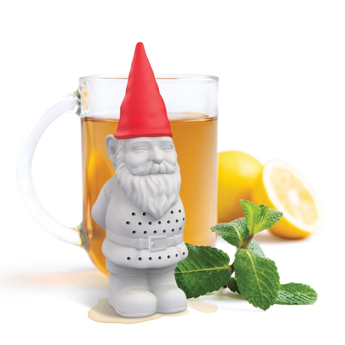 Bearded garden gnome plastic tea infuser in grey with a red pointed hat and perforated coat, shown beside a mug of tea, lemons, and mint on a white background.