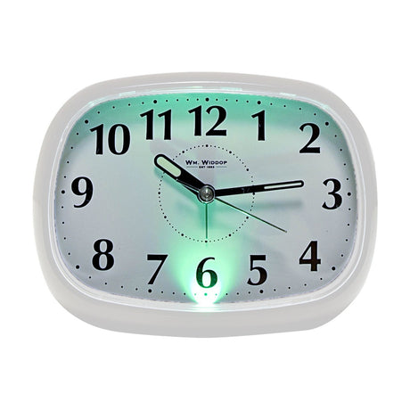 Oval silent alarm clock with white plastic case, white dial with bold black numerals and luminous-tipped hands, illuminated in green light, shown on a plain white background.