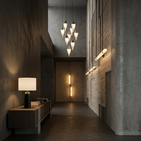 A modern hallway with concrete walls, geometric pendant lights, vertical wall lights, and a wooden console table featuring the Arvello 1 Light Minimal Marble Table Lamp in white & black and books on the left side.
