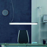 Bath A LED Linear Pendant Light in white, a slim tube-shaped fixture with polycarbonate diffuser, suspended above a desk in an office setting.