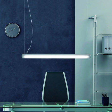 Bath A LED Linear Pendant Light in white, a slim tube-shaped fixture with polycarbonate diffuser, suspended above a desk in an office setting.