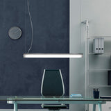 Bath A LED Linear Pendant Light in white, a slim tube suspended above a glass desk in an office setting with a dark wall, wall clock, and shelving unit.