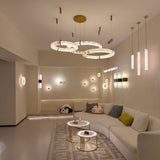 Aureon LED Triple Ring Alabaster Chandelier in brushed brass, three staggered circular rings suspended over a living room seating area with warm ambient glow.