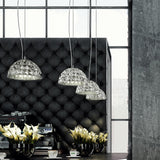 Deco Crystal Pendant Light in chrome, three dome-shaped faceted crystal shades hung at staggered heights above a dining table in a dark tufted-leather interior.
