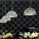 Deco Crystal Pendant Light in chrome, dome-shaped faceted crystal shades at varying drop heights above a dining area with tufted dark wall panelling.