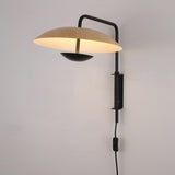 Niori Ginger LED Wall Light in black and brown with illuminated round wood-toned disc shade, slim metal arm, wall mount, and inline switch cord.