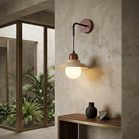 The Rovano 1 Light Hanging Dome Travertine Wall Light in Walnut Brown & Light Beige illuminates a minimalist wooden console table in a neutral room with indoor plants and large glass windows.