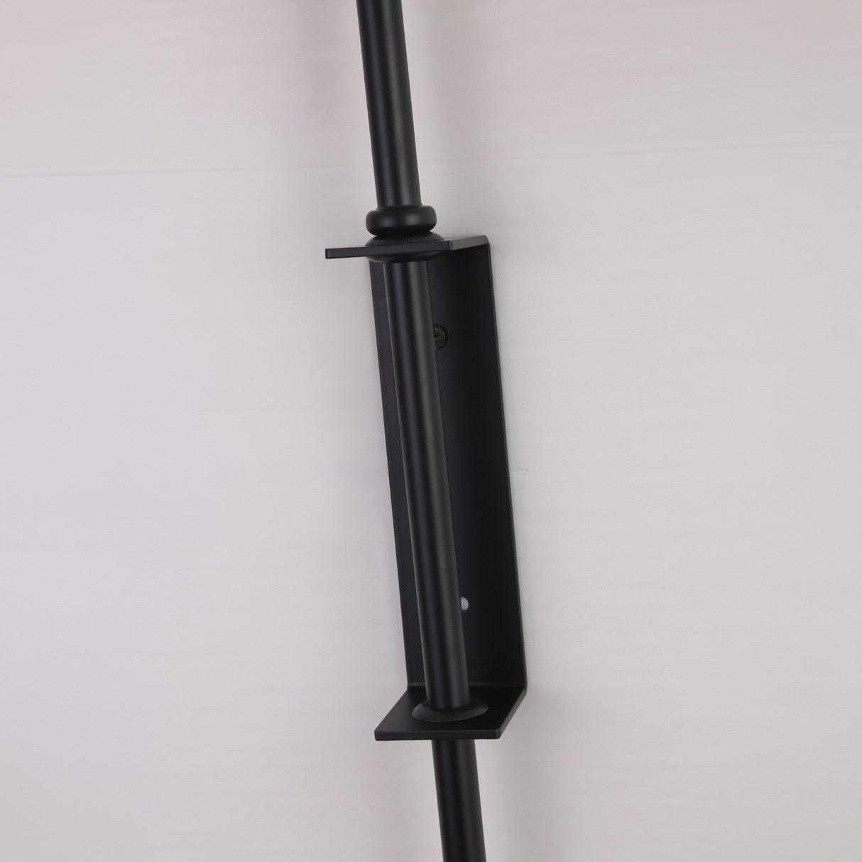 Close-up of the Niori Ginger LED Wall Light's black metal wall bracket and vertical rod mounted against a plain light background.