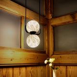 Halvessa LED 2 Light Alabaster Dimmable Pendant Light in black, two glowing marbled globes on a U-shaped bracket with twin cables, shown against wood-panelled walls.