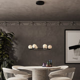Halvessa LED 6 Light Alabaster Chandelier in black, round ring design with glowing alabaster globes, shown above a dining table in a neutral-toned room.