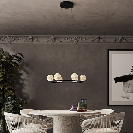 Halvessa LED 6 Light Alabaster Chandelier in black, round ring design with glowing alabaster globes, shown above a dining table in a neutral-toned room.