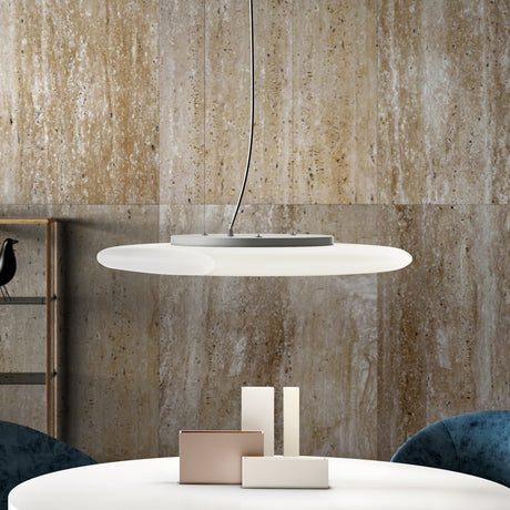Moon LED Pendant Light in white, a wide disc-shaped fixture with a crescent-like notch, hung on slim wires above a dining table in a stone-walled interior.