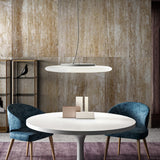 Moon LED Pendant Light in white, a wide disc-shaped fixture with a crescent notch, suspended on slim wires above a round dining table in a modern interior.