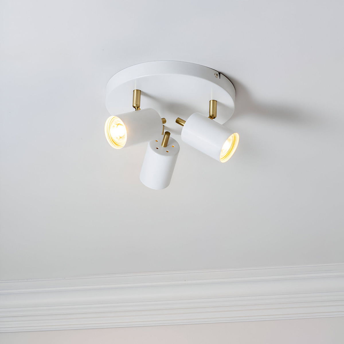Endon Radnor 3 Light Round Spotlight in matt white with brass fittings and three adjustable GU10 heads, mounted on a pale ceiling with cornice below.