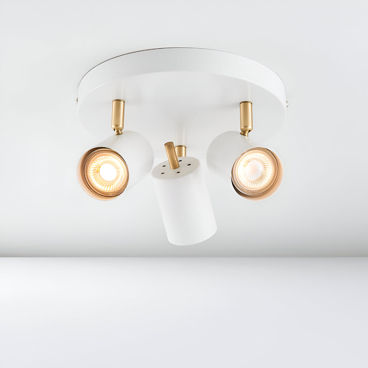 Endon Radnor 3 light round spotlight in matt white with brass fittings and three adjustable GU10 heads, shown on a plain ceiling.