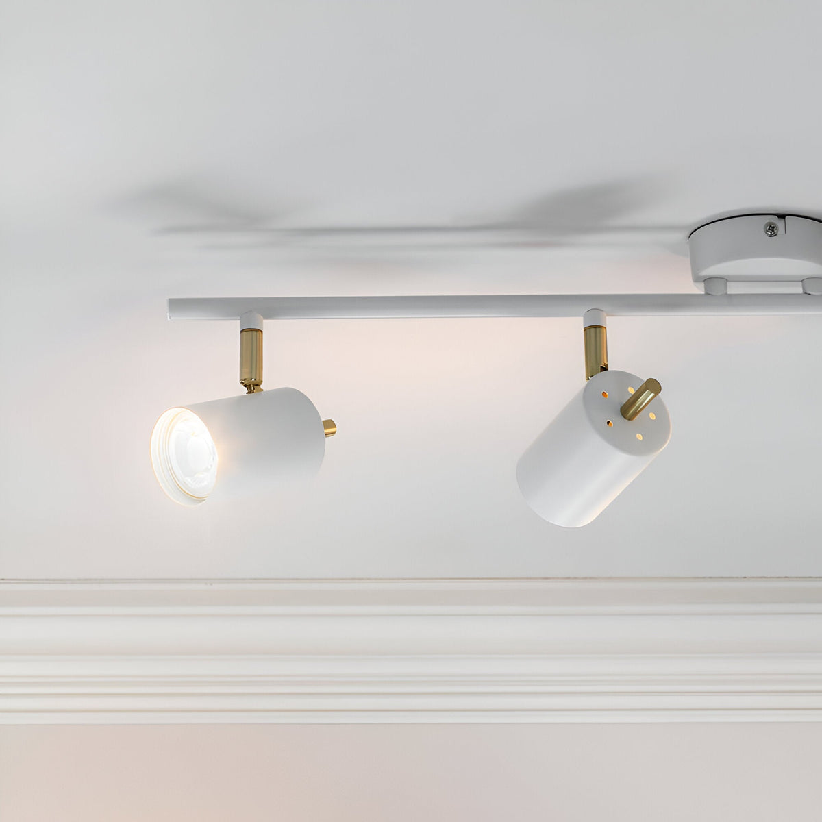 Endon Radnor spotlight bar in matt white with brass detailing, showing two adjustable GU10 heads angled from a slim ceiling-mounted bar.