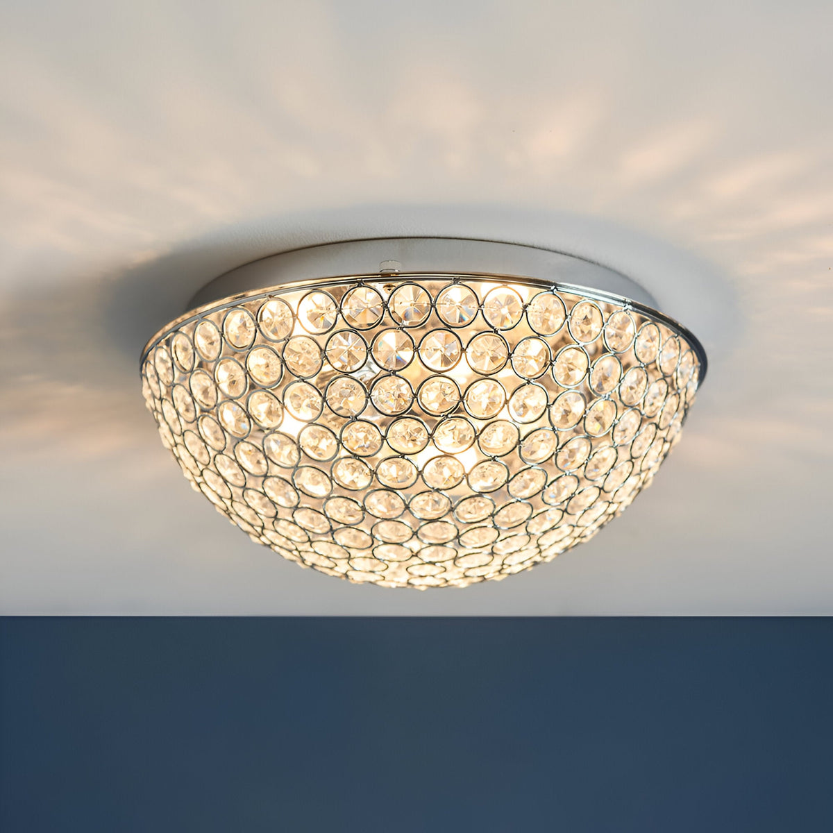 Endon Cordelia 3 light crystal flush bathroom ceiling light in chrome, illuminated on a white ceiling with a dark blue wall below.
