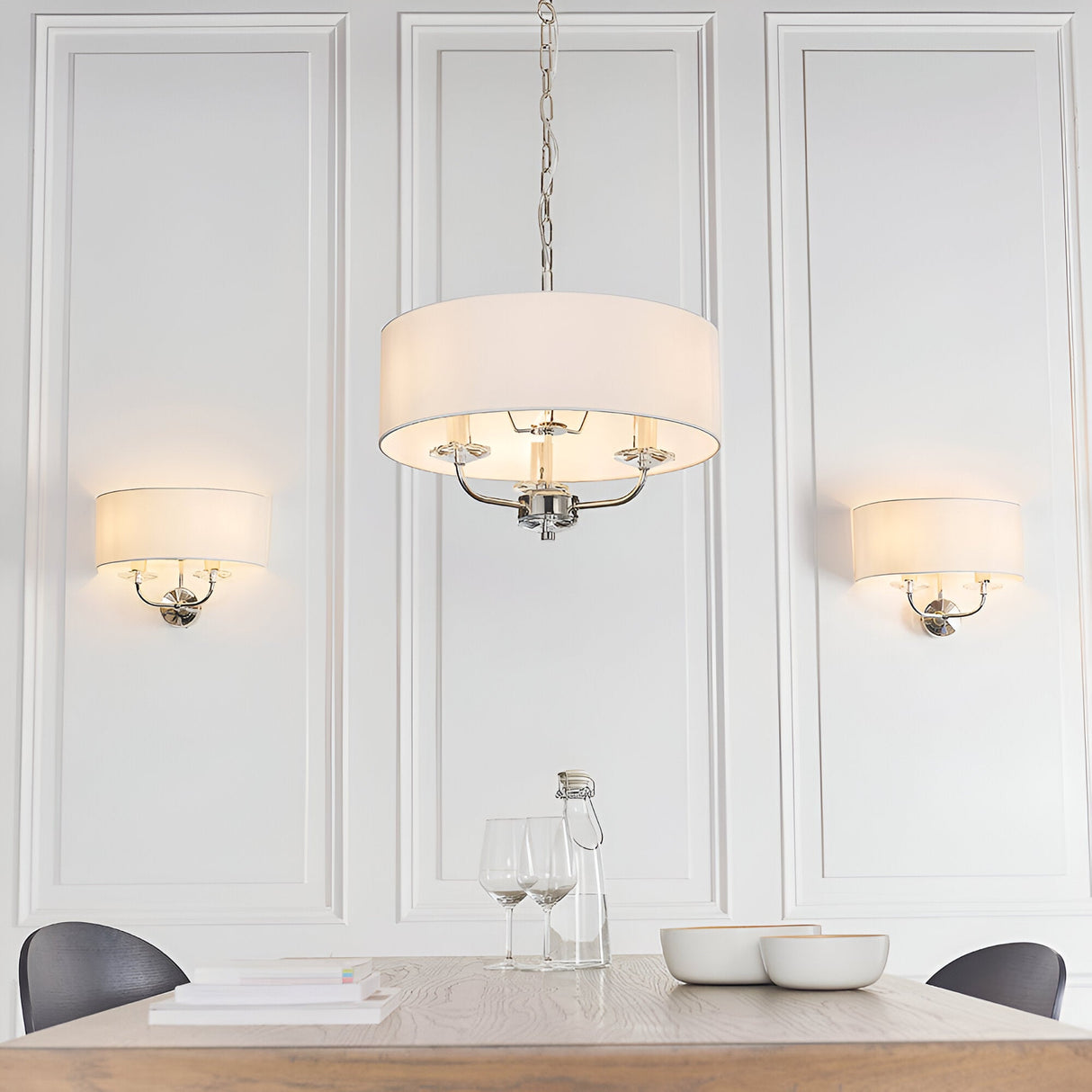 Endon Castdon 3 light pendant in nickel with white drum shade and crystal detail, shown above a dining table between two matching wall lights.