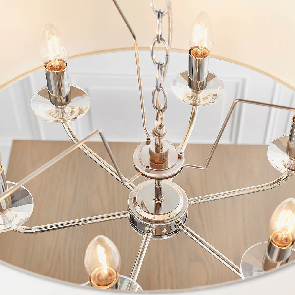 Castdon 6-light pendant close-up showing nickel arms, crystal bobeches, exposed E14 bulbs and central chain, with white shade visible above.