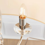 Close-up of the Castdon 6 Light Pendant's nickel arm with crystal bobeche and lit E14 candle bulb, against a cream faux silk shade.