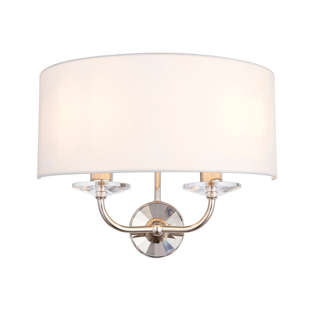 Castdon 2 Light Wall Light in nickel, with a white faux silk semi-circular shade and crystal accents on curved arms, shown on a plain white background.