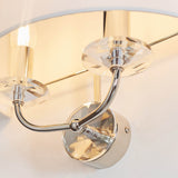 Close-up of the Castdon 2 Light Wall Light in nickel, showing curved metal arms with faceted crystal accents beneath a white fabric shade.