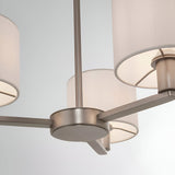 Close-up of the Bexley 3 Light Pendant in matt nickel, showing curved metal arms with white faux silk cylinder shades against a plain light background.