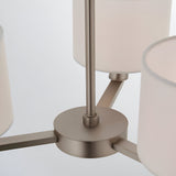 Close-up of the Bexley 3 Light Pendant's central matt nickel fitting, showing curved metal arms and white fabric shades on a plain white background.