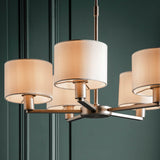 Bexley 5 Light Pendant in matt nickel with white faux silk drum shades, shown close-up against a dark panelled wall.