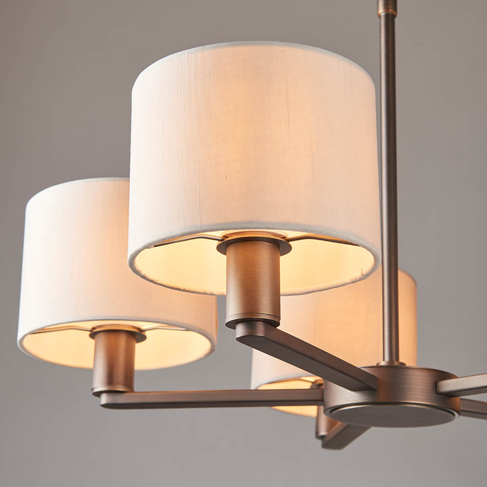 Bexley 5 Light Pendant in matt nickel, close-up of curved arms with cylindrical vintage white faux silk shades against a grey background.