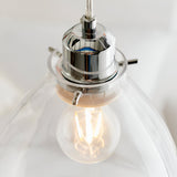 Close-up of Endon Brackmere pendant light showing polished chrome gimbal, clear glass shade and lit E27 filament bulb.