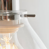 Close-up of Endon Brackmere pendant light showing polished chrome gimbal fitting, clear glass shade, and glowing E27 filament bulb inside.