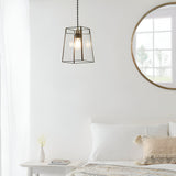 Endon Aldwell antique brass pendant light with faceted clear glass shade, hung in a bright white bedroom beside a round wood-framed mirror.