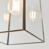 Close-up of the Endon Aldwell pendant light showing the antique brass trim joining clear faceted glass panels around a glowing filament bulb.