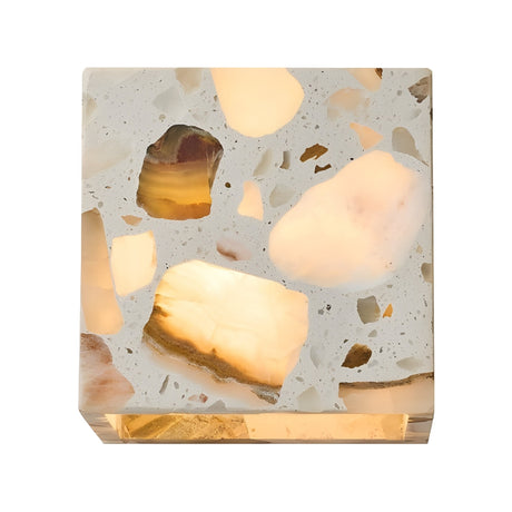 The Terrano 1 Light Cube Travertine Wall Light in light beige features a cube shape with large, irregular translucent stone pieces, casting a soft warm glow—an eye-catching modern fixture for contemporary interiors.