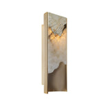 The Veloris LED Medium Carved Alabaster Wall Light in brushed brass and soft white features a rectangular gold frame, marble-like panel reminiscent of Spanish alabaster, and glows warmly from above.