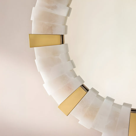 A close-up of the Lumessa LED Alabaster Mirror Light in Brushed Brass & Soft White, featuring frosted panels and gold accents. Its modern, geometric design stands out against a plain, light-colored background.