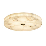 The Veltrix LED Large Round Alabaster Flush Ceiling Light features a smooth, marbled surface that emits a soft white glow, highlighted by a small brushed brass accent in the center for an elegant touch.